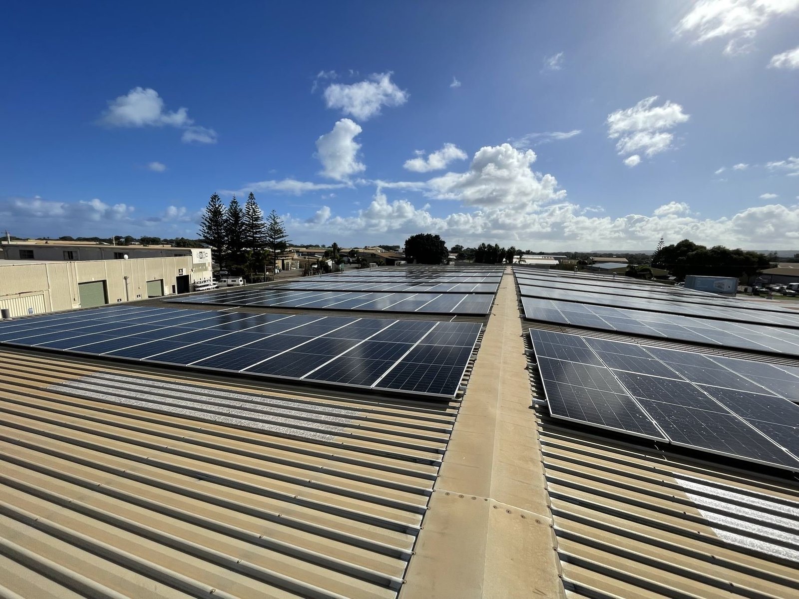 Wide commercial rooftop solar array under blue sky